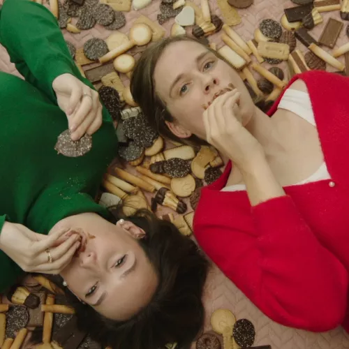 Werkneemsters van VGD op de grond tussen koekjes. 