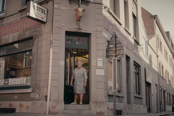 Een oudere dame staat in de deuropening van hotel De Bonte Os.