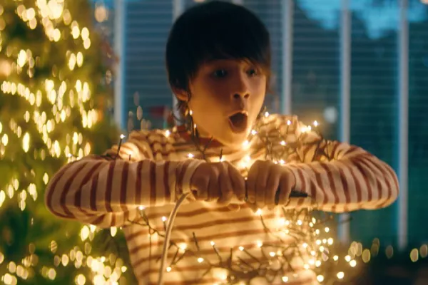 Een jongen steekt kerstlichtjes aan.