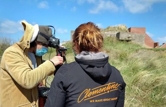 Regisseur en drone operator staan aan een bunker, ze kijken op de monitor.