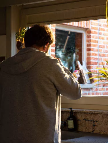 Een acteur staat aan een aanrecht en kijkt door het raam.