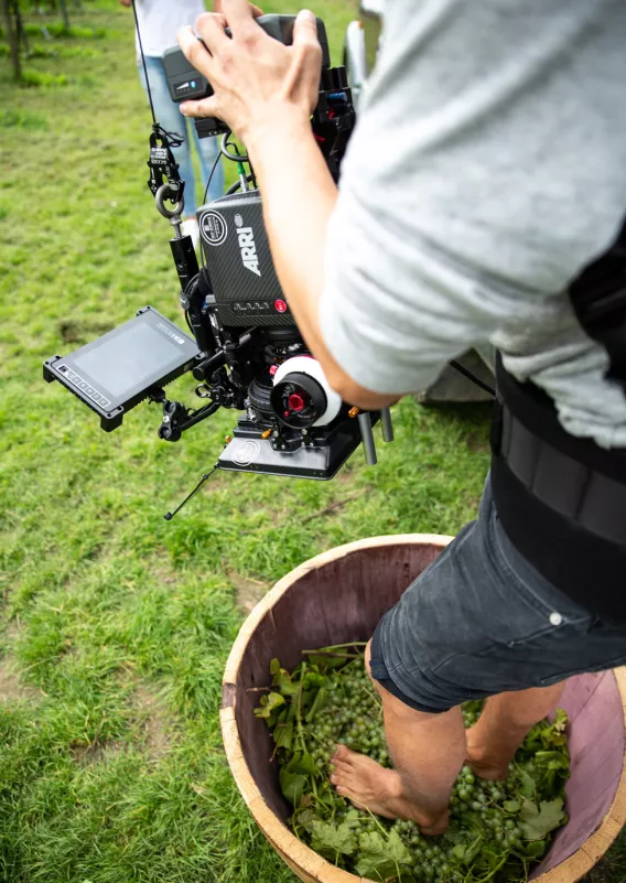 De cameraman is druiven aan het pletten met zijn blote voeten en filmt het.