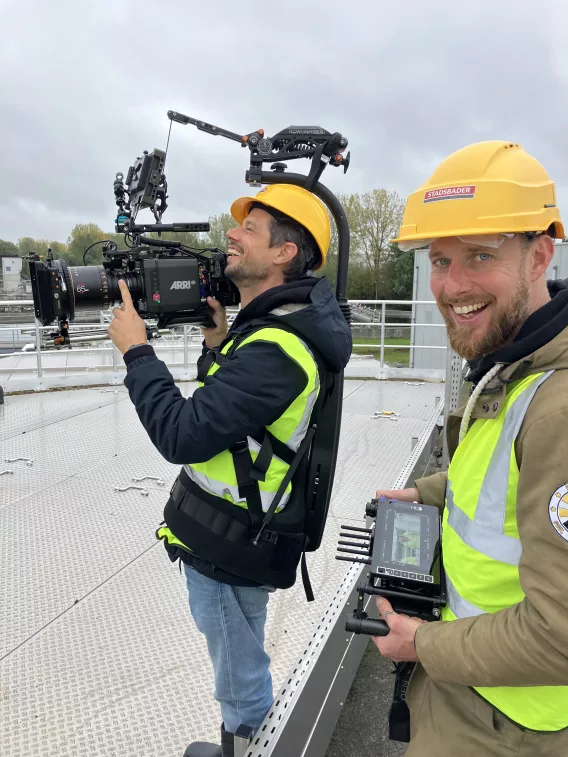 De regisseur en cameraman zijn aan het lachen.