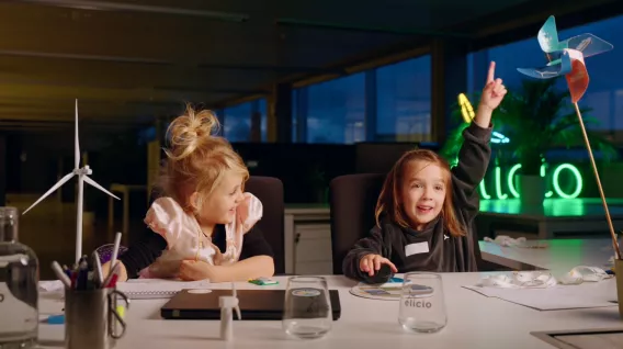 Twee kinderen van Elicio werknemers aan een bureau