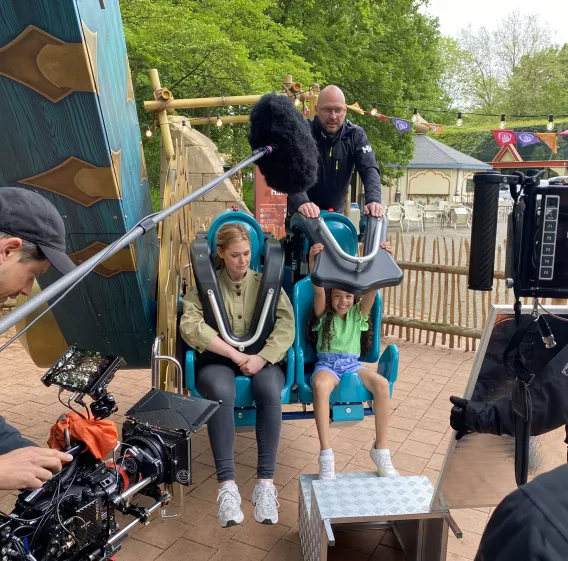 Een meisje zit naast een jonge vrouw op de Hampi, ze worden gefilmd.