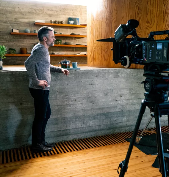 Acteur staat aan een toog, hij wordt gefilmd.